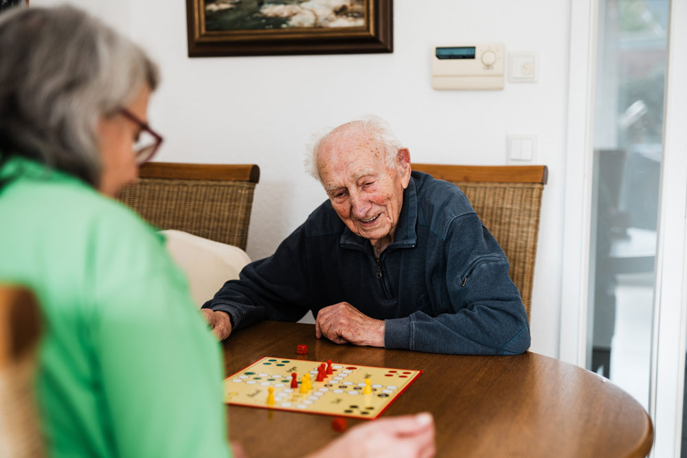 sanamed Haushaltshilfe, Senior spielt mit Betreuerin ein Brettspiel, Pflegedienst Havixbeck